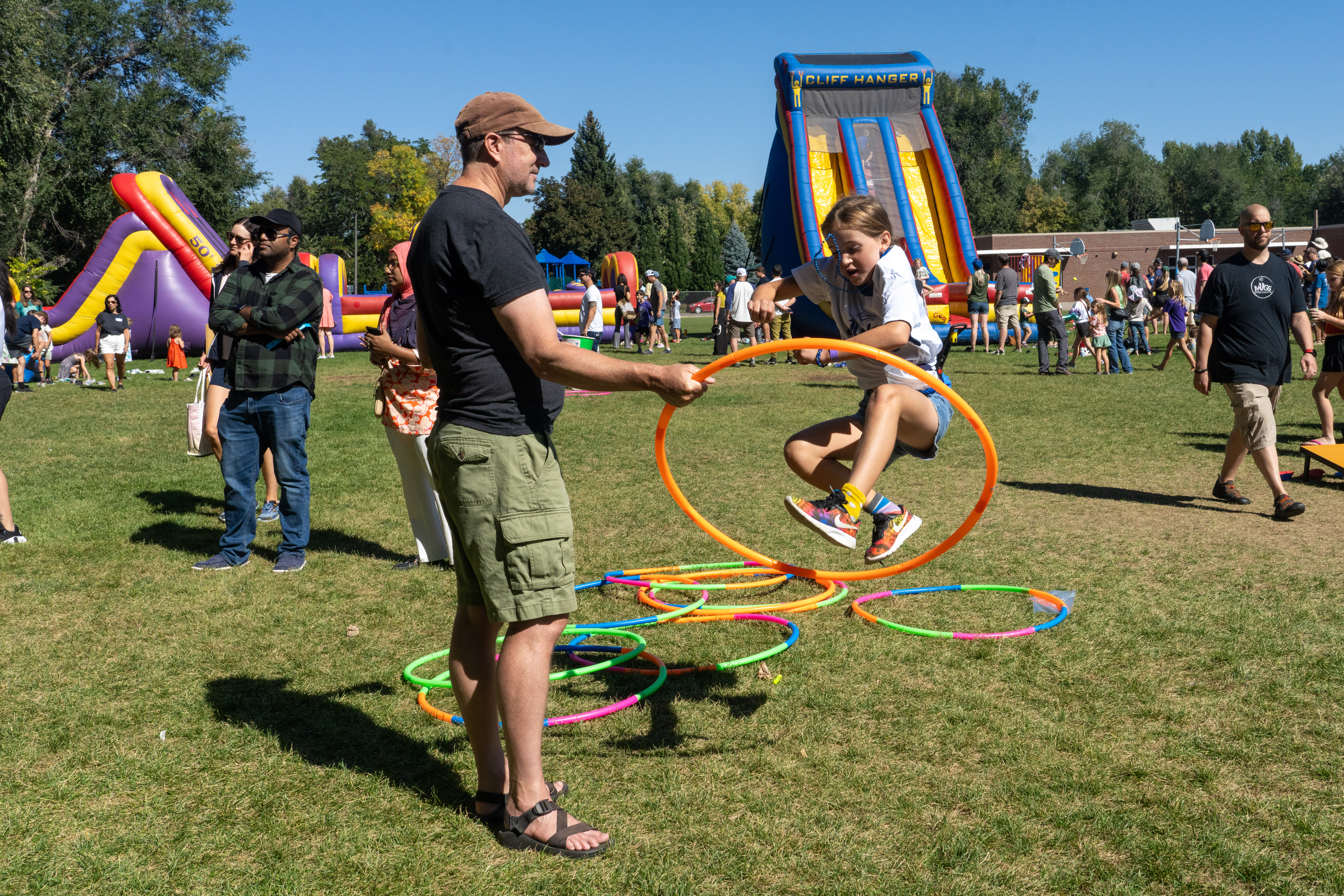 A Dunn student jumps through a hulu hoop that a man is holding. 