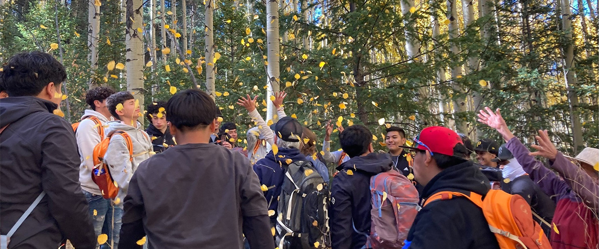 Students throw leaves in the air during an environmental leadership class.