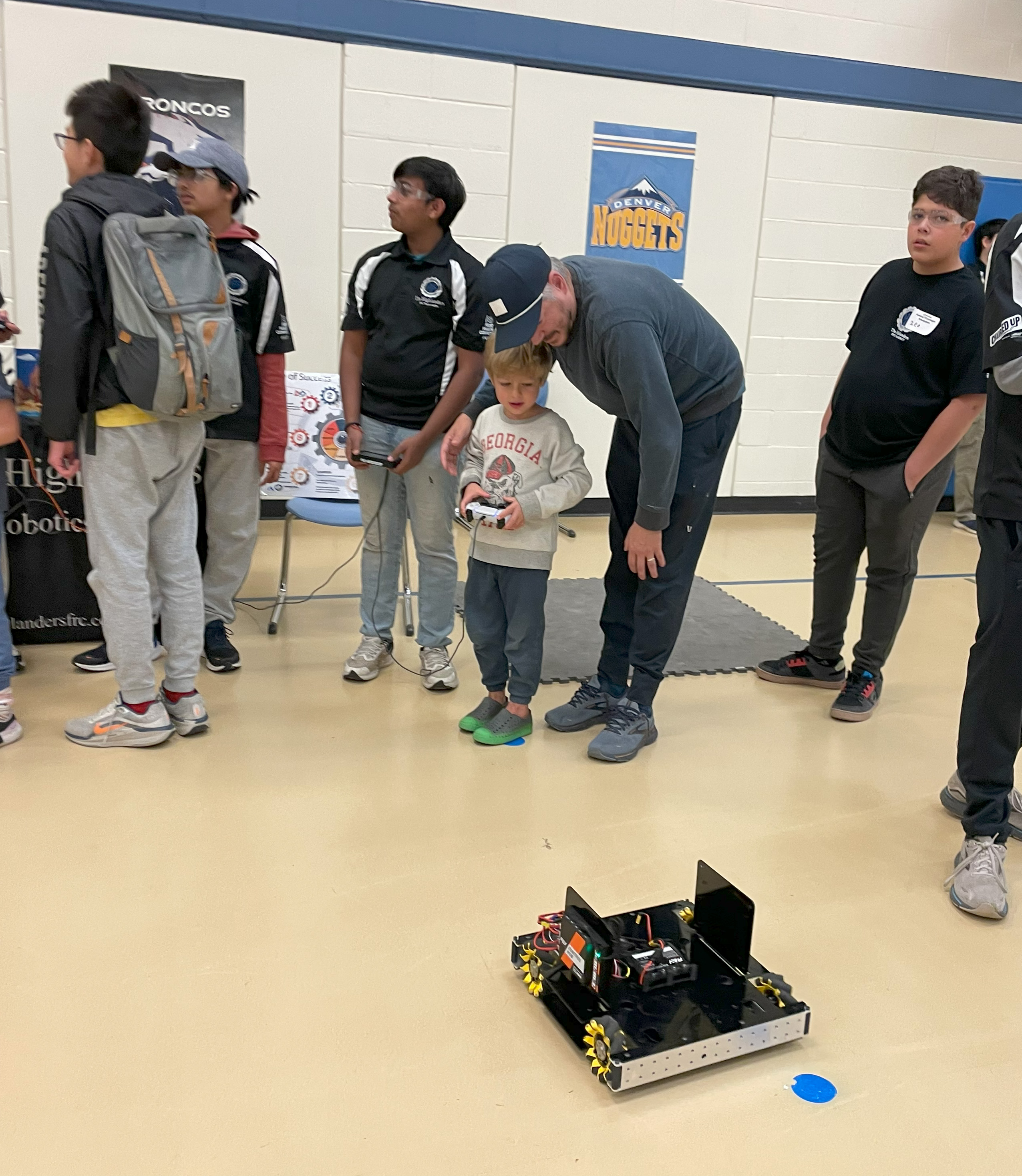 A father and young son drive a robotics vehicle. 