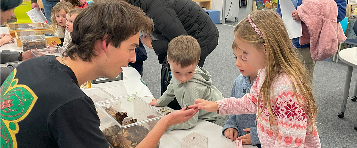 Three young students look in awe at bugs.