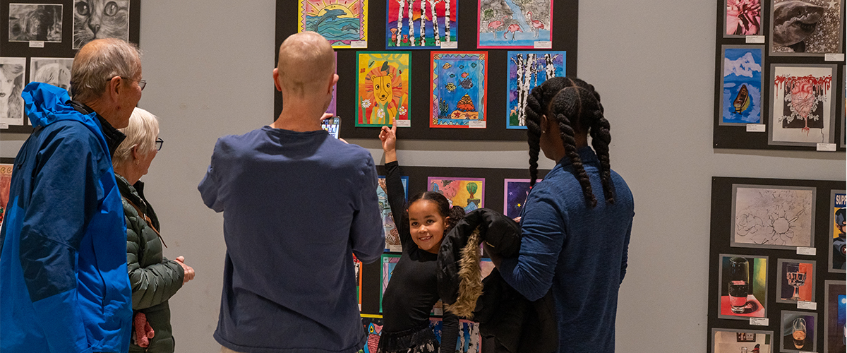 A young girl points to her artwork at the Creative Arts exhibit at the mall. 