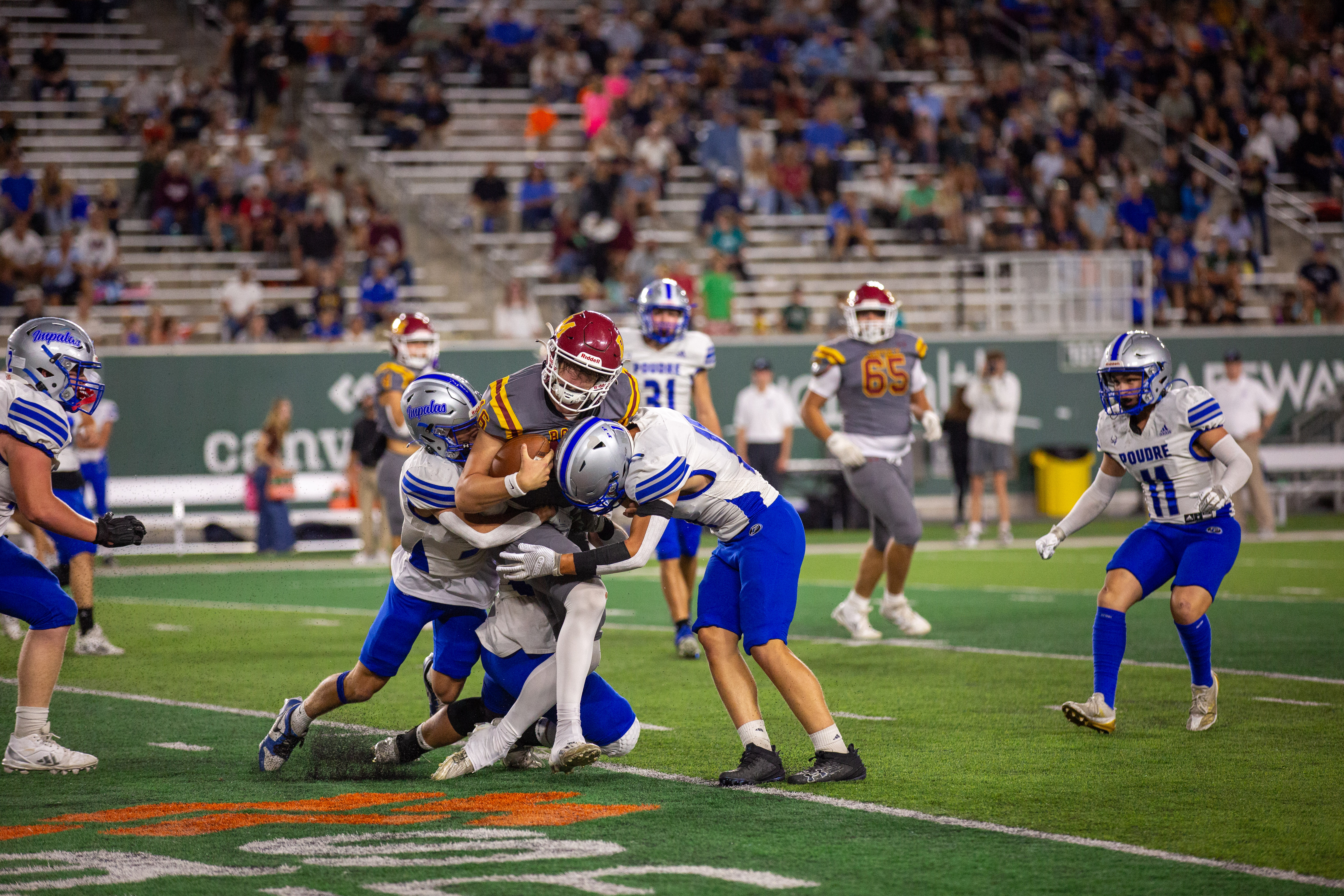 A football player with the ball is tackled. 