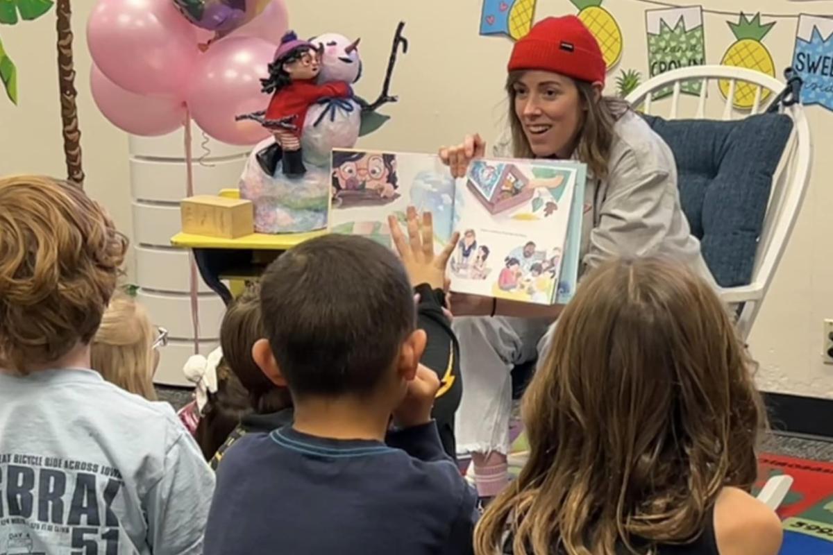 A young adult reads a book to Bauder Elementary students.