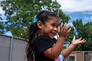 A preschool student plays with bubbles. 