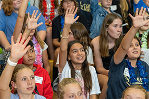 Middle school students with raised hands.