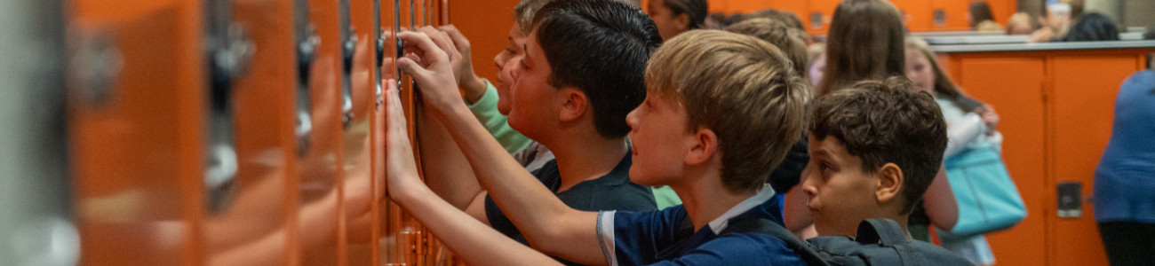 Young boys working to unlock their lockers for school